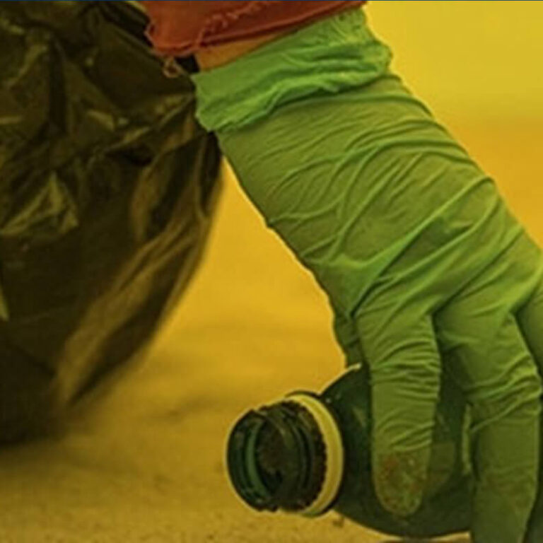 Mão com luva realizando manejo de material durante atividade ambiental